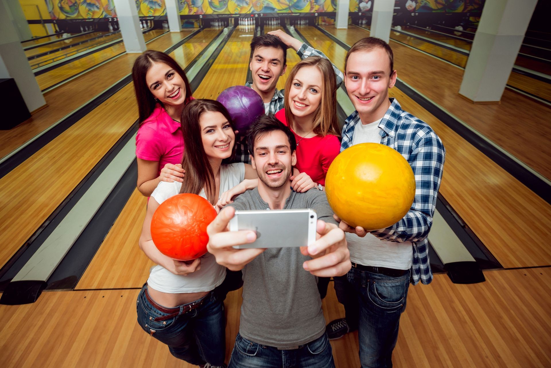 Cheerful friends at the bowling alley with the balls. Selfie